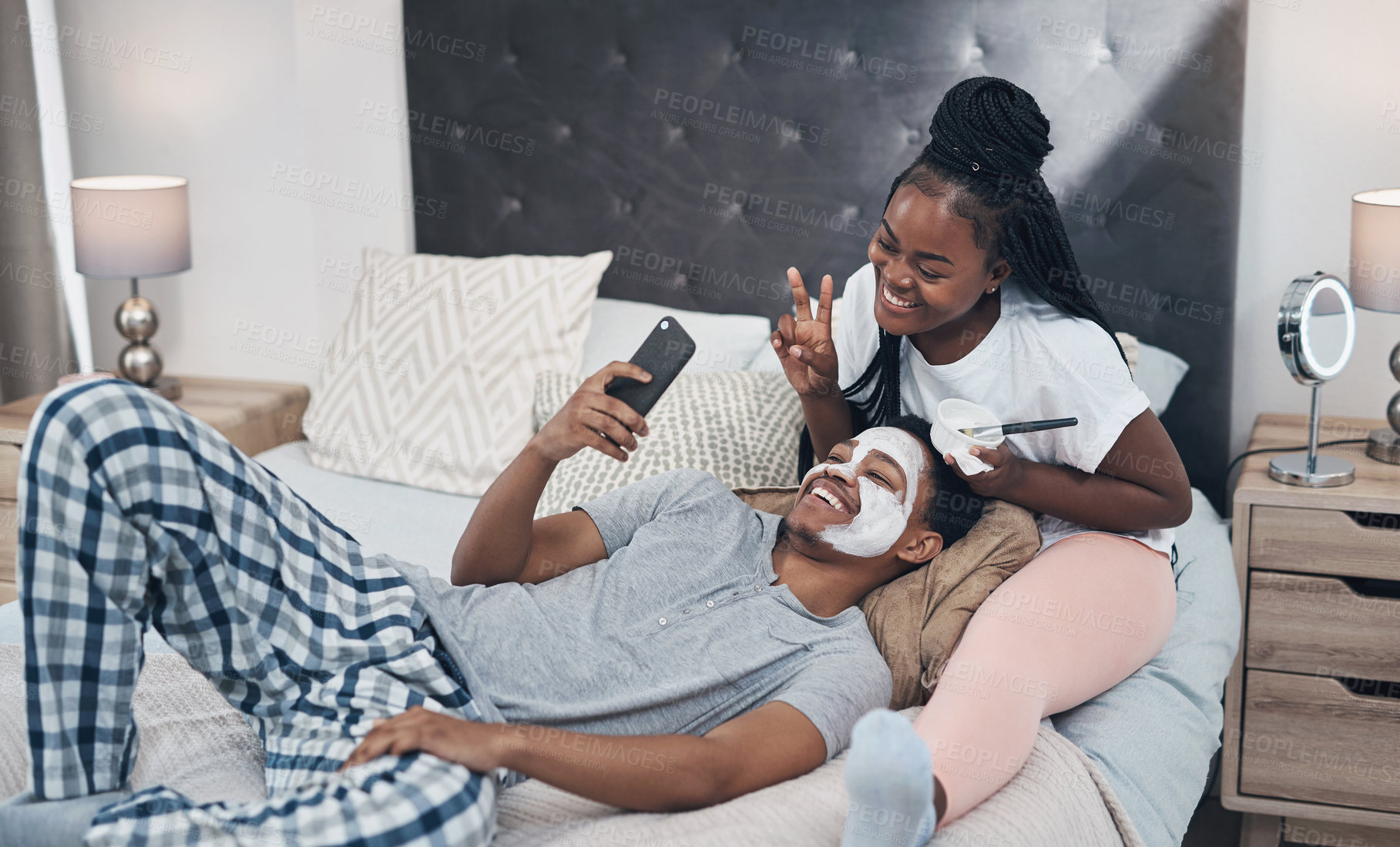 Buy stock photo Shot of a young couple taking selfies while getting homemade facials together at home