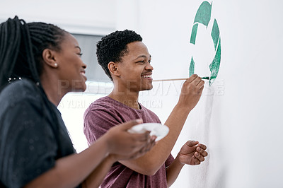 Buy stock photo Shot of a young couple painting a recycle symbol on a wall