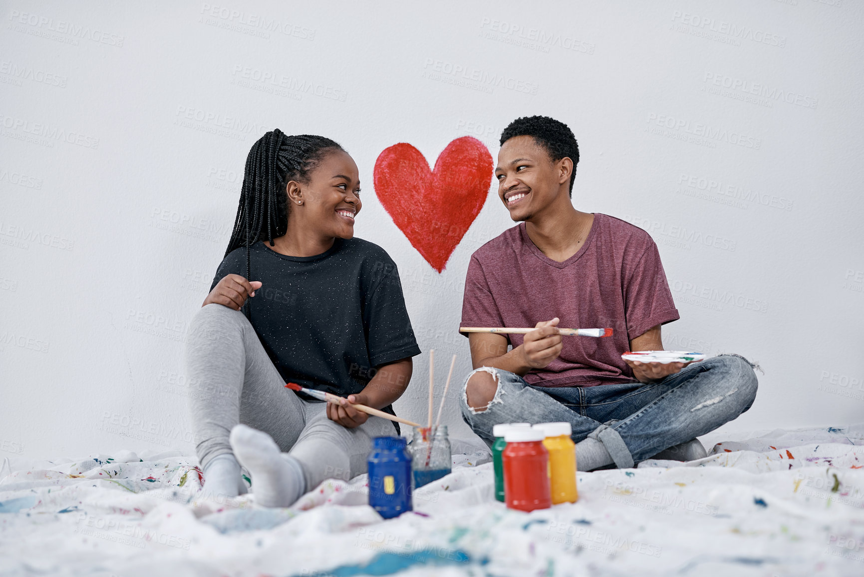 Buy stock photo Shot of a young couple painting a heart on a wall