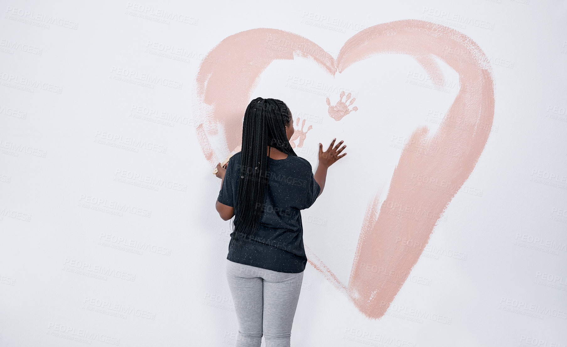 Buy stock photo Shot of a young woman painting a heart on a wall