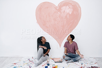 Buy stock photo Shot of a young couple painting a heart on a wall