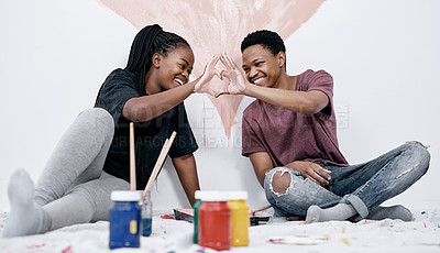 Buy stock photo Shot of a young couple making a heart shaped gesture while painting a wall pink
