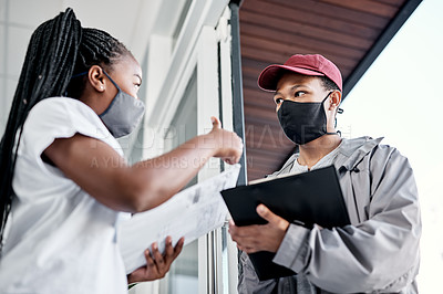 Buy stock photo Shot of a masked young woman showing thumbs up after receiving a delivery at home