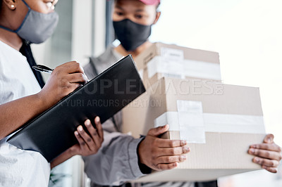 Buy stock photo Shot of a masked young woman signing for a delivery received at home