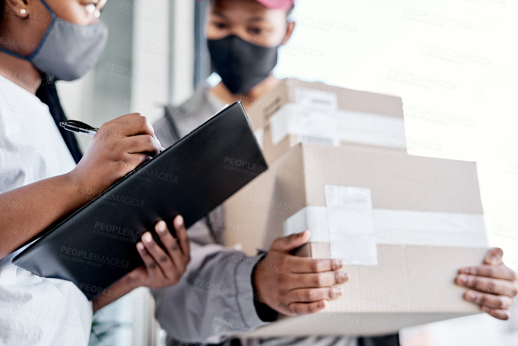 Buy stock photo Shot of a masked young woman signing for a delivery received at home