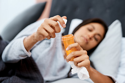 Buy stock photo Shot of a young woman taking medication while recovering from an illness in bed at home