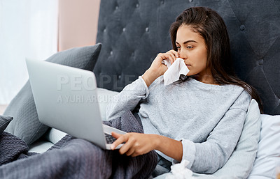 Buy stock photo Shot of a young woman using a laptop while recovering from an illness in bed at home