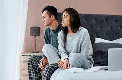 Buy stock photo Shot of a young couple looking thoughtful while recovering from an illness in bed at home
