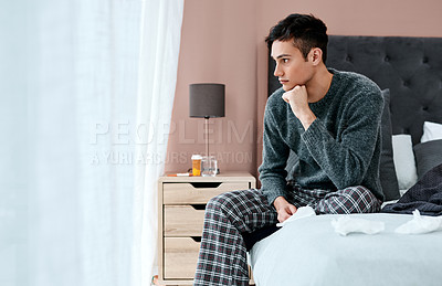 Buy stock photo Shot of a young man looking thoughtful while recovering from an illness in bed at home