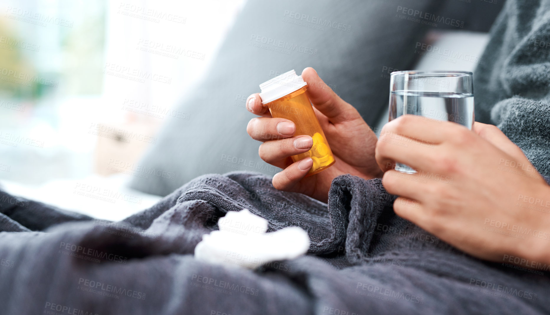 Buy stock photo Shot of an unrecognisable man taking medication while recovering from an illness in bed at home