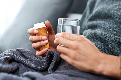 Buy stock photo Shot of an unrecognisable man taking medication while recovering from an illness in bed at home