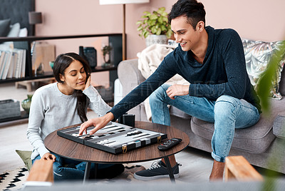 Buy stock photo Shot of a young couple playing a game of backgammon at home