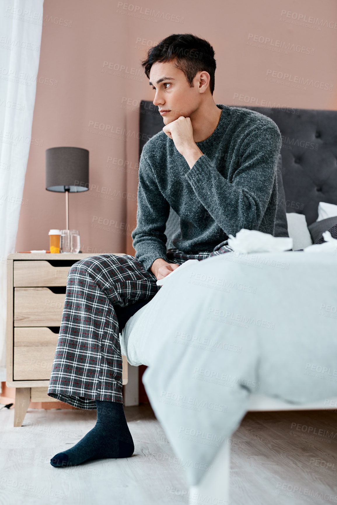 Buy stock photo Shot of a young man looking thoughtful while recovering from an illness in bed at home