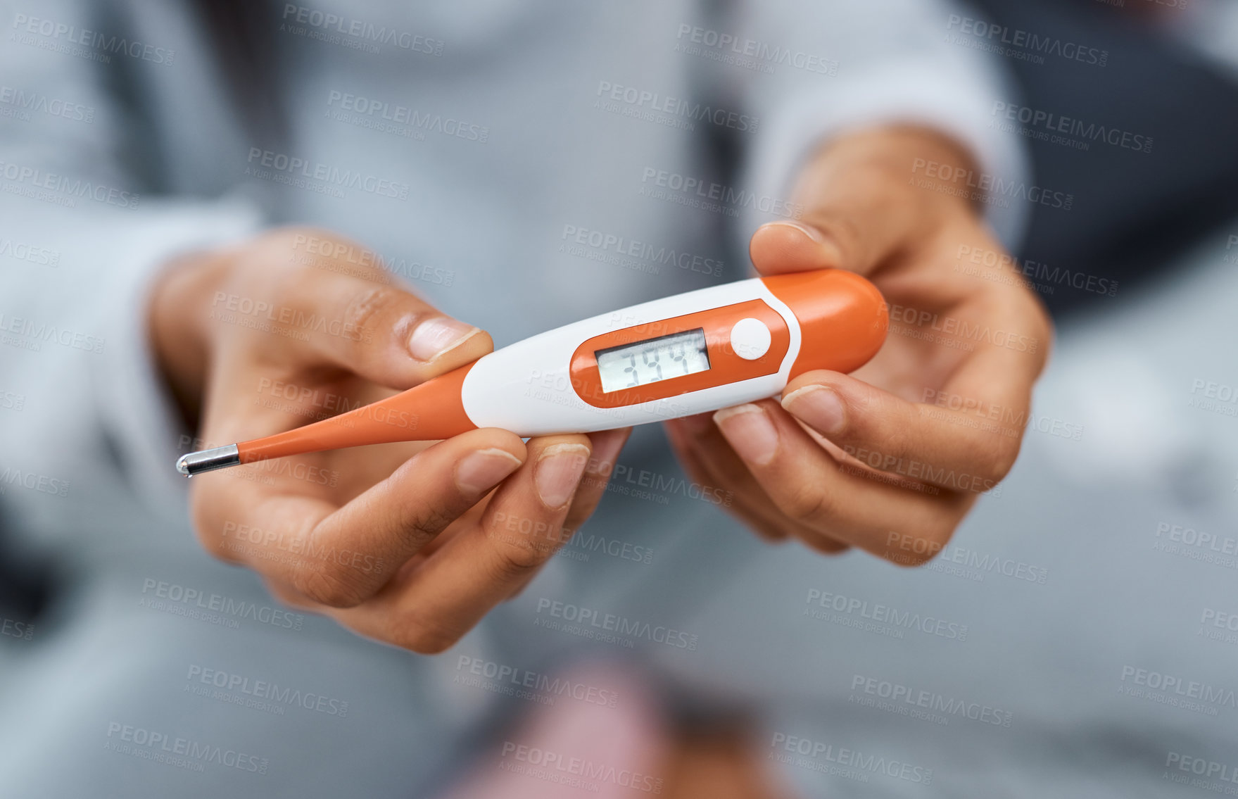 Buy stock photo Shot of an unrecognisable woman taking her temperature while recovering from an illness in bed at home
