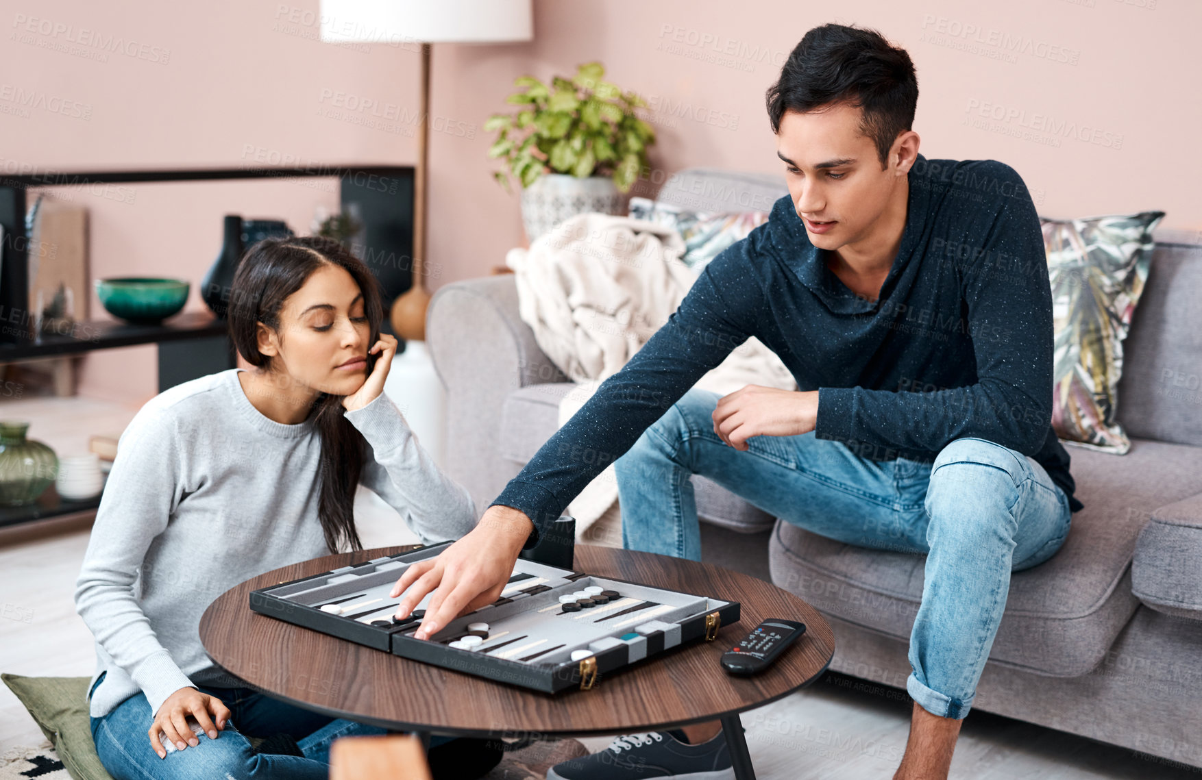 Buy stock photo Shot of a young couple playing a game of backgammon at home