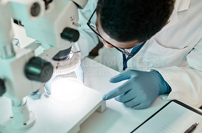 Buy stock photo Shot of a young scientist using a microscope in a lab