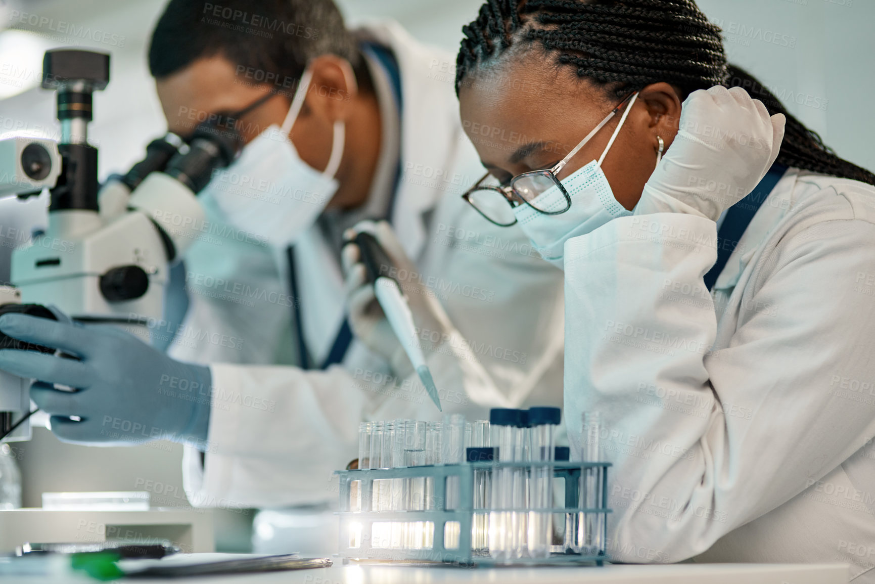 Buy stock photo Shot of a young scientist working with samples alongside a colleague in a lab