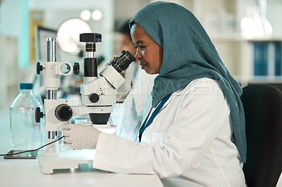 Buy stock photo Shot of a young scientist using a microscope in a lab