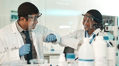 Buy stock photo Shot of two scientists bumping elbows while working together in a lab