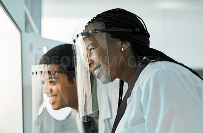 Buy stock photo Shot of two scientists wearing face shields while working together in a lab