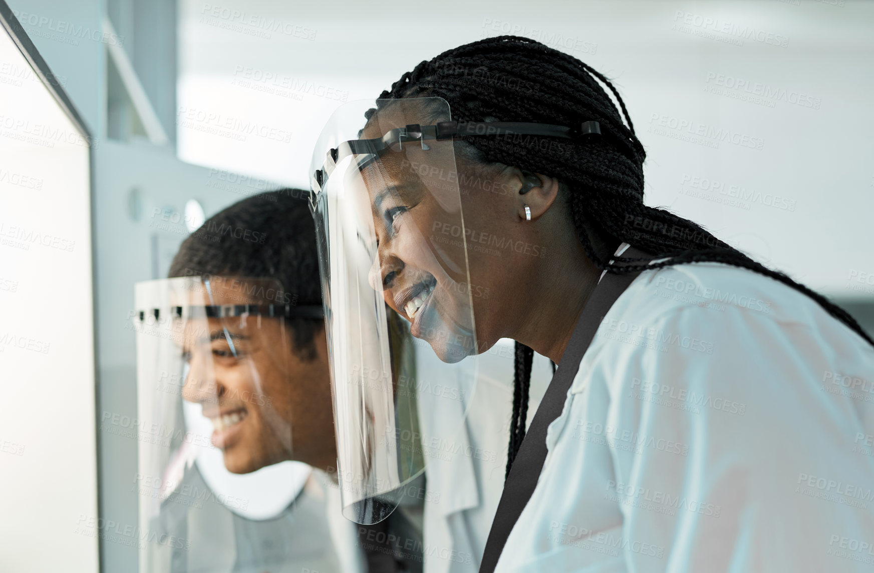 Buy stock photo Shot of two scientists wearing face shields while working together in a lab