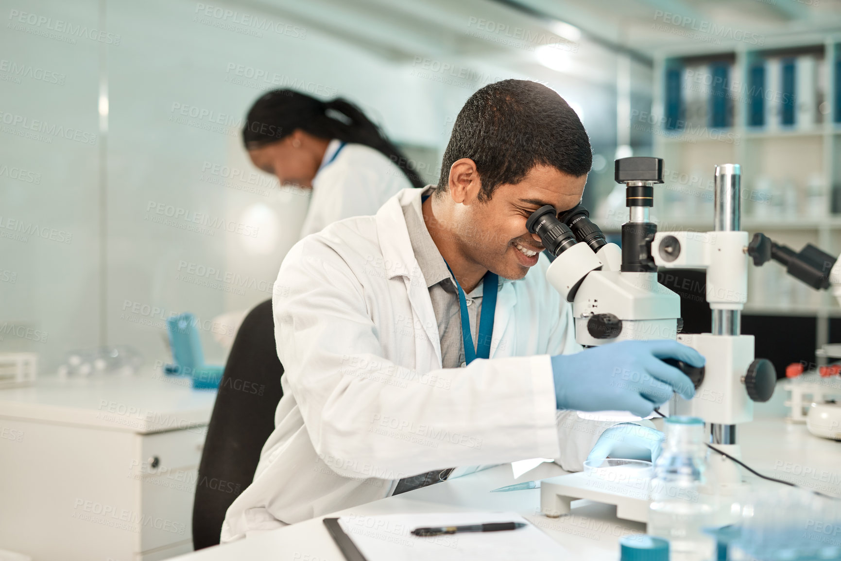 Buy stock photo Shot of a young scientist using a microscope in a lab