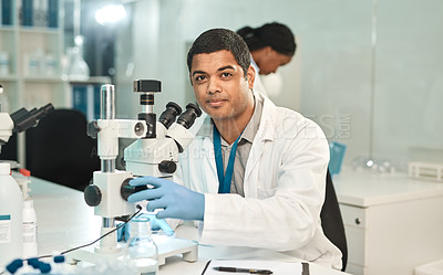 Buy stock photo Portrait of a young scientist using a microscope in a lab