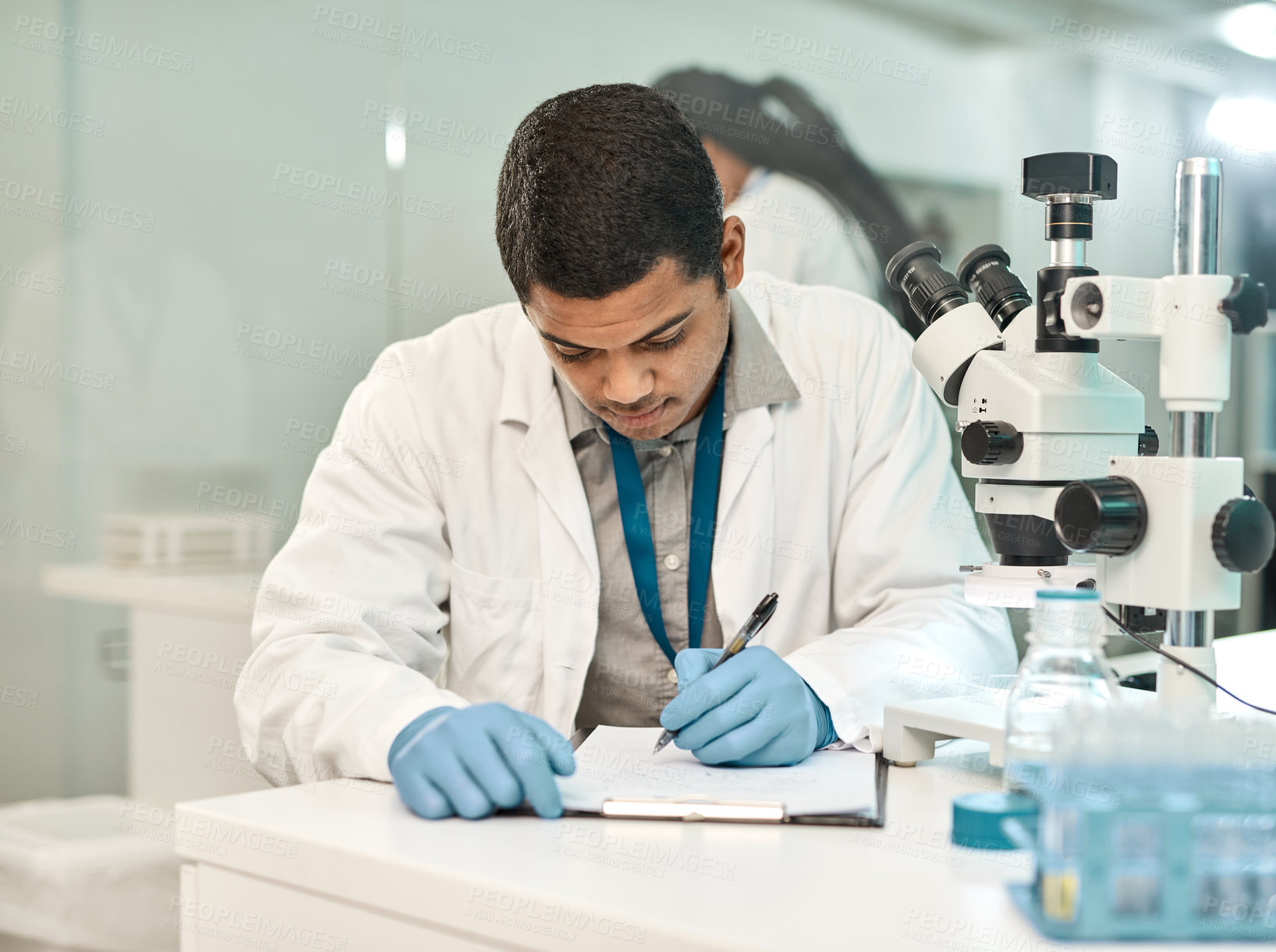 Buy stock photo Shot of a young scientist writing notes while working in a lab