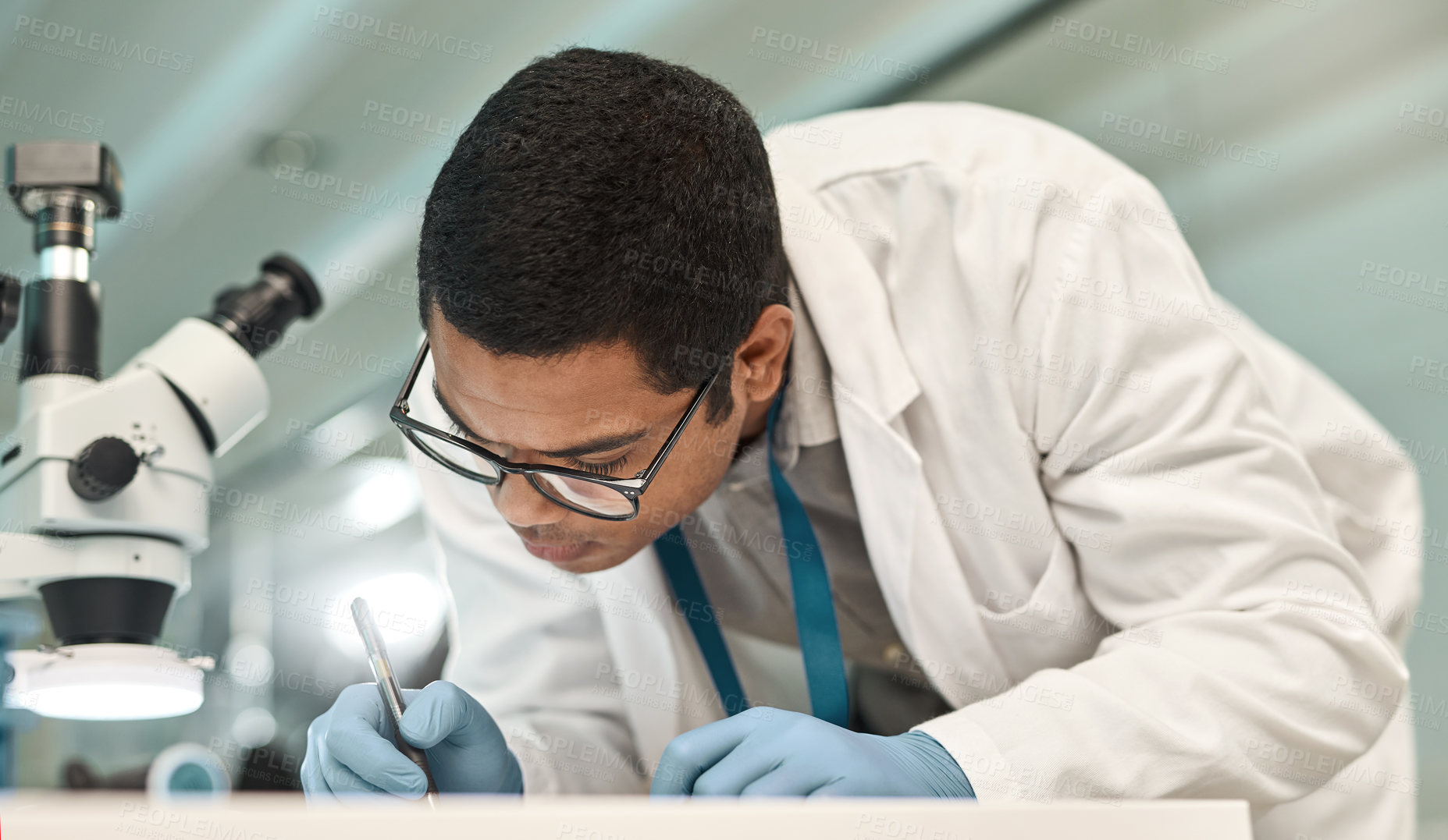 Buy stock photo Shot of a young scientist writing notes while working in a lab