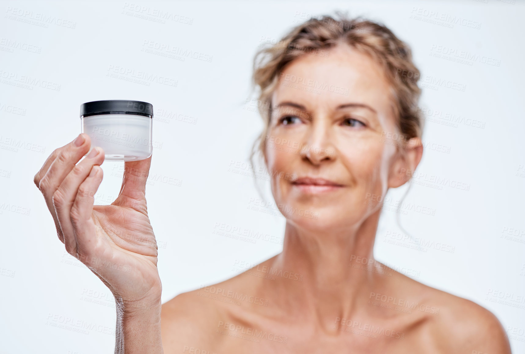 Buy stock photo Shot of a mature woman holding up a beauty product against a while background