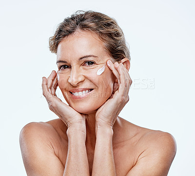 Buy stock photo Shot of a mature woman posing with moisturiser on her face