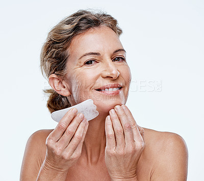 Buy stock photo Cropped shot of a mature woman using a Qua Sha on her face