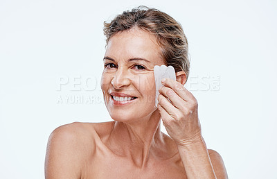 Buy stock photo Cropped shot of a mature woman using a Qua Sha on her face