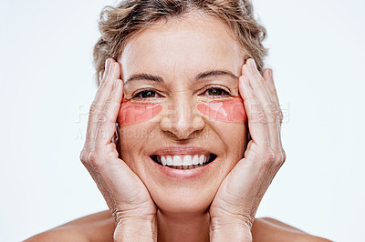 Buy stock photo Shot of a mature woman wearing under-eye gel patches while posing against a white background