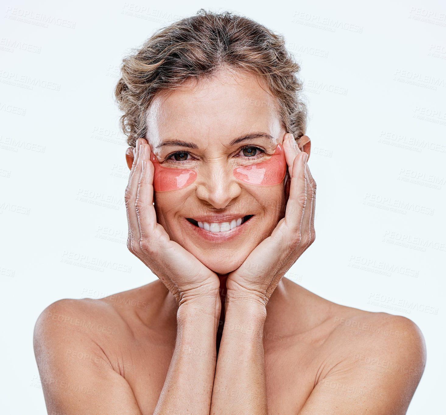 Buy stock photo Shot of a mature woman wearing under-eye gel patches while posing against a white background