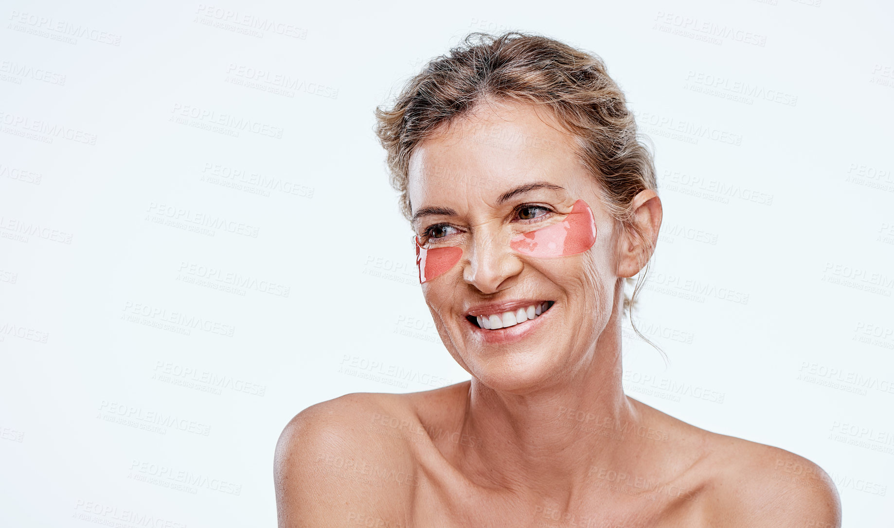 Buy stock photo Shot of a mature woman wearing under-eye gel patches while posing against a white background