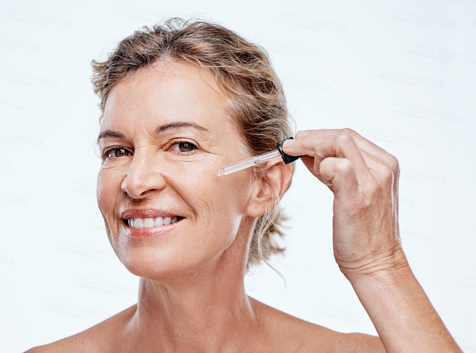Buy stock photo Shot of a mature woman posing with a serum dropper against her face