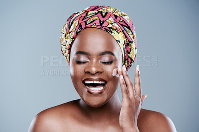 Buy stock photo Studio shot of a beautiful young woman applying face lotion against a grey background