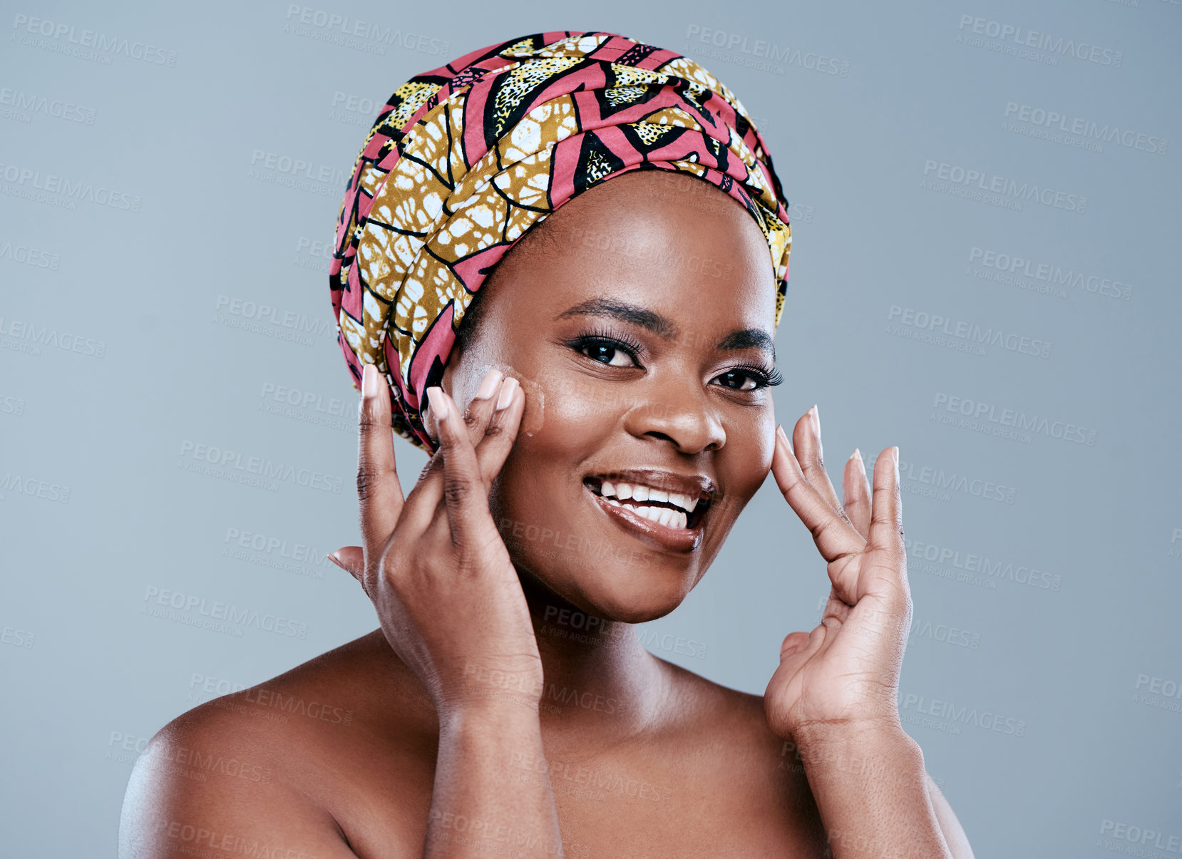 Buy stock photo Studio portrait of a beautiful young woman applying face lotion against a grey background