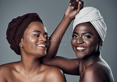 Buy stock photo Studio portrait of two beautiful young women posing against a grey background