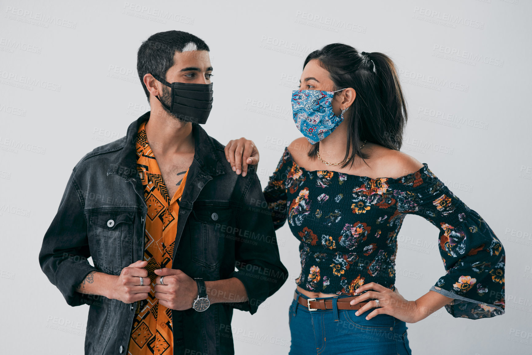 Buy stock photo Studio shot of a masked young man and woman posing against a grey background