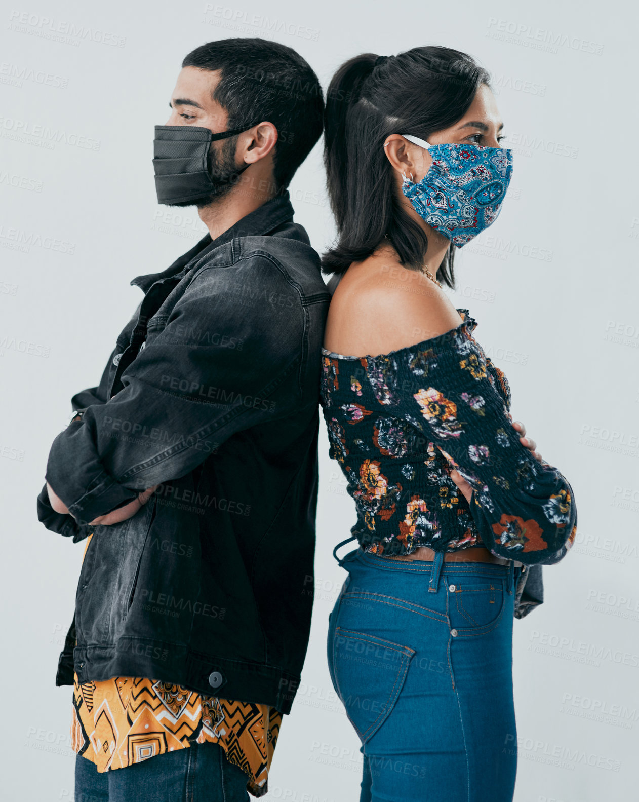 Buy stock photo Studio shot of a masked young man and woman posing against a grey background