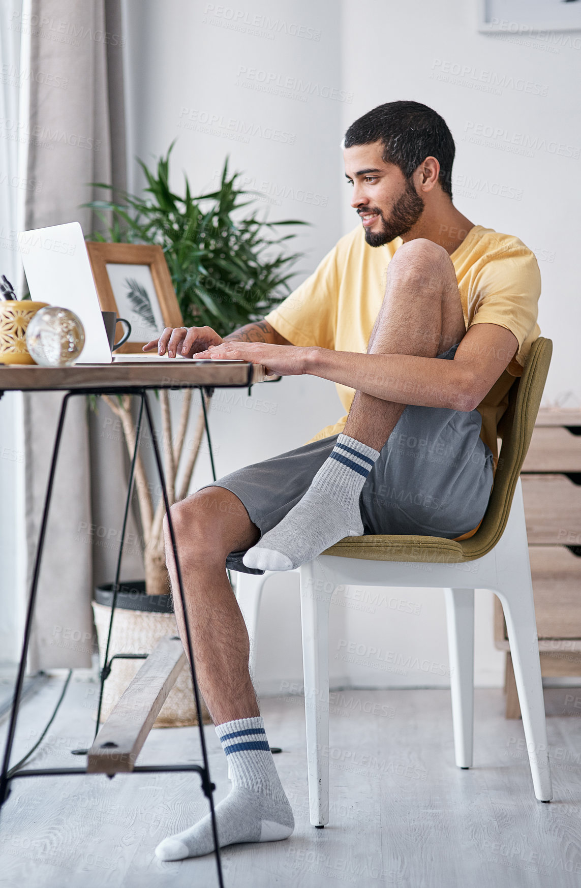 Buy stock photo Shot of a young man using a laptop while working from home