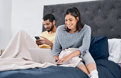 Buy stock photo Shot of a young couple using their wireless devices in bed