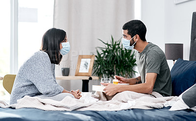 Buy stock photo Shot of a masked young couple having breakfast in bed while recovering from an illness at home
