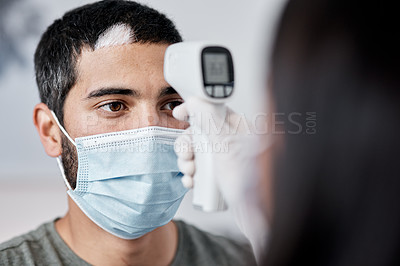 Buy stock photo Shot of a young man getting his temperature taken by his wife while recovering from an illness at home