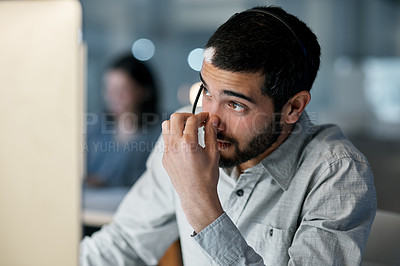 Buy stock photo Shot of a young man feeling stressed while using a headset and computer late at night in a modern office