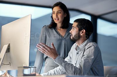 Buy stock photo Shot of a young woman helping her colleague in a call centre late at night