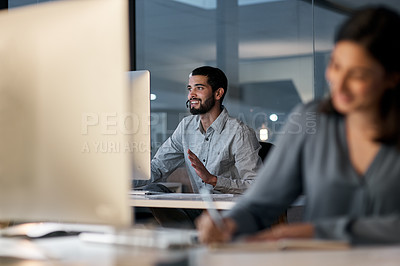 Buy stock photo Shot of a young man using a headset and computer late at night in a modern office