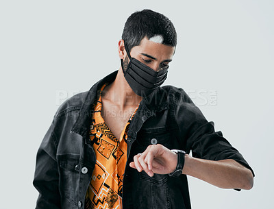 Buy stock photo Studio shot of a masked young man checking the time against a grey background
